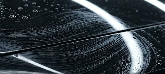 Pintura preta sob a luz do estúdio, com marcas finas visíveis ao redor do reflexo