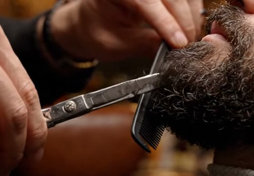 Tesoura e pente aparando a ponta de uma barba cheia