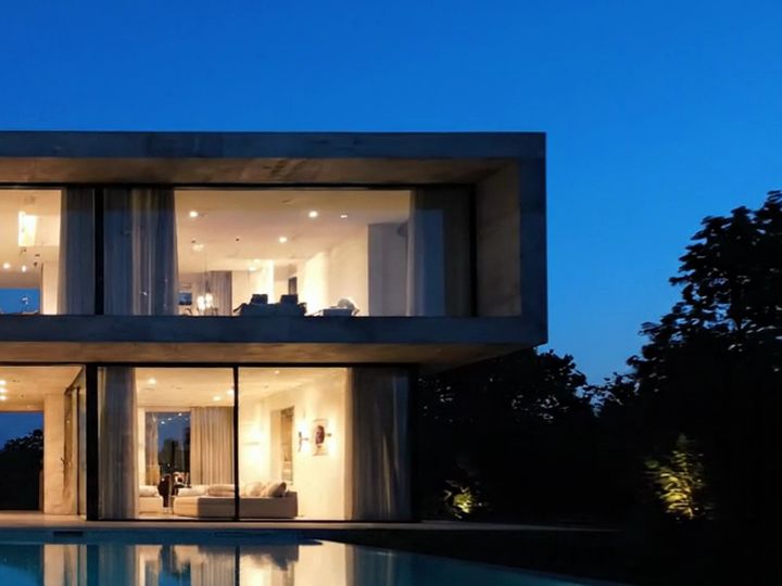 Pavimento superior envidraçado sob o céu azul do anoitecer, com árvores ao lado