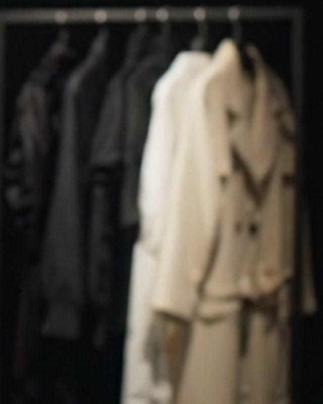 Arara com casacos escuros e trenches off-white pendurados